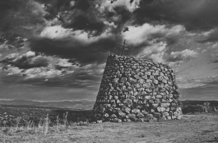 Nuraghe in pietra nel paesaggio sardo sotto un cielo nuvoloso, in bianco e nero